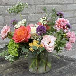 Mixed bouquet of pink, orange, purple, and white flowers in a glass vase