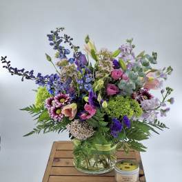 Mixed bouquet in a glass vase with a small candle beside it