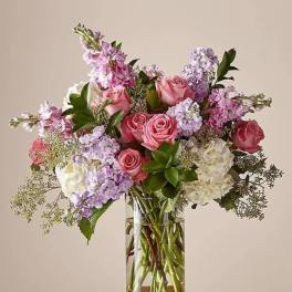 Pink and lavender roses with white blooms in a clear glass vase