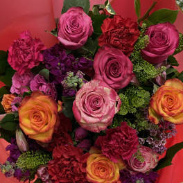 Bouquet of pink, orange, and purple roses with carnations in red wrapping