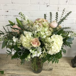 Large bouquet of pale hydrangeas and blush roses in a glass vase