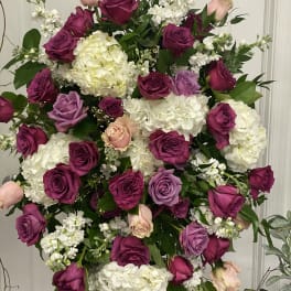 Large standing spray of pink, purple, and white roses with white hydrangeas