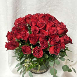 Bouquet of red roses in a glass vase with mixed greenery
