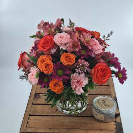 Mixed bouquet of roses, carnations, and daisies in a clear glass vase