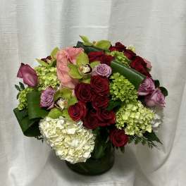Mixed bouquet of red and pink roses with hydrangeas in a glass vase