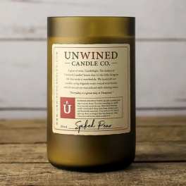 Amber glass candle jar with a cream label on a wooden surface