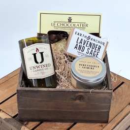 Gift basket with chocolates, candles, and soap in a wooden crate