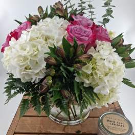 Pink roses and white hydrangeas in a glass vase with greenery
