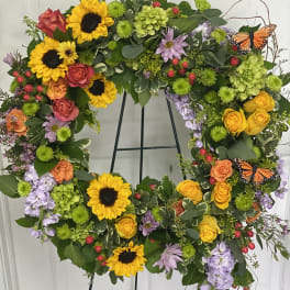 Heart-shaped floral wreath with sunflowers, roses, and butterflies