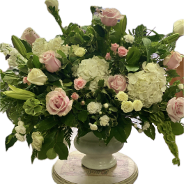 Pink and white roses with hydrangeas in a white urn vase