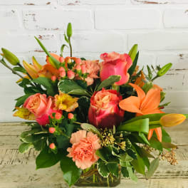 Mixed bouquet of pink roses, lilies, and carnations in a glass vase