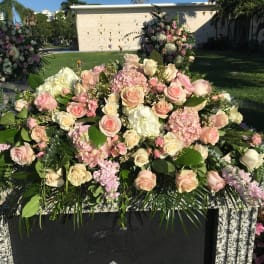 Large pink and white floral arrangement on a stone memorial