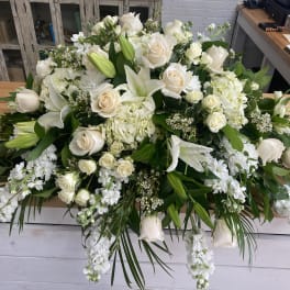 Large white floral arrangement with roses and lilies on a table