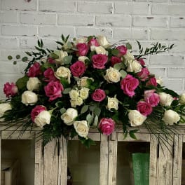 Large bouquet of pink and white roses with greenery on a wooden cabinet