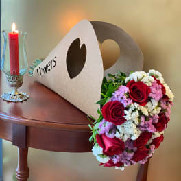 Red rose bouquet beside a lit candle in a glass holder