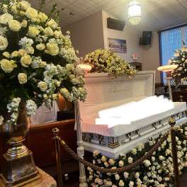 White rose funeral display around a casket with matching floral sprays