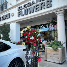 Standing bouquet of red roses with white orchids outside a flower shop
