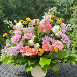 Mixed pink and white flowers in a white vase with yellow accents
