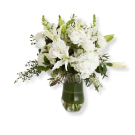 White floral arrangement in a glass vase with lilies and roses