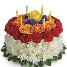 Tiered floral cake with red, orange, and white flowers and yellow candles