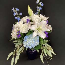 White lilies and blue hydrangea in a dark vase