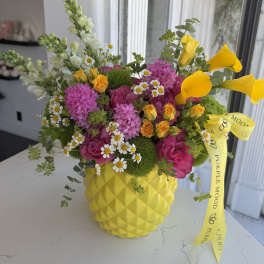 Bright mixed bouquet in a yellow textured vase with a ribbon bow