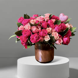 Pink and blush roses arranged in a brown glass vase with a glitter heart pick