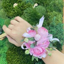 Pink floral wrist corsage with ribbon on a person's wrist