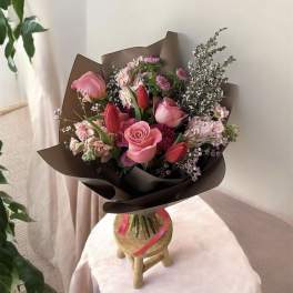 Pink and red mixed bouquet wrapped in dark paper