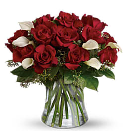 Bouquet of red roses with white calla lilies in a clear glass vase
