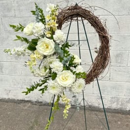 White floral arrangement on a grapevine crescent wreath stand