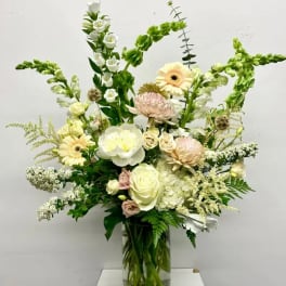 Tall mixed bouquet in a clear glass vase with white and pale pink flowers