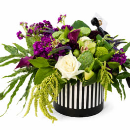 Purple and white floral arrangement in a striped round box