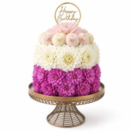 Tiered pink, white, and purple flower arrangement with a Happy Birthday topper