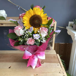 Bouquet with a large sunflower, pink roses, and a bright pink ribbon