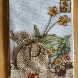 Decorative card with pressed flowers and a burlap pouch on a textured white background