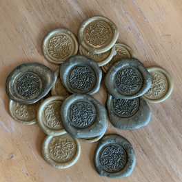 Stack of floral-patterned wax seals in gold and dark gray
