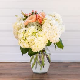 Peach roses and white hydrangeas in a clear glass vase