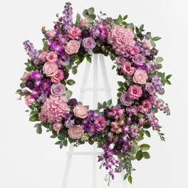Pink and purple floral wreath on a white stand