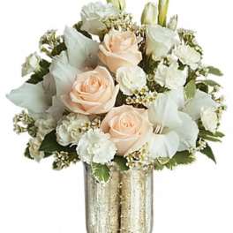 Peach roses and white flowers arranged in a gold vase