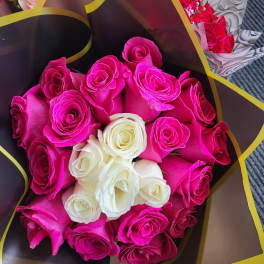 Bouquets of hot pink and white roses wrapped in dark paper with gold trim