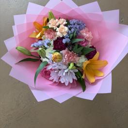 Mixed bouquet with pink, purple, and orange flowers wrapped in pink paper