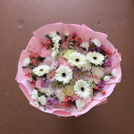 Pink-wrapped bouquet of white gerbera daisies and mixed pastel flowers