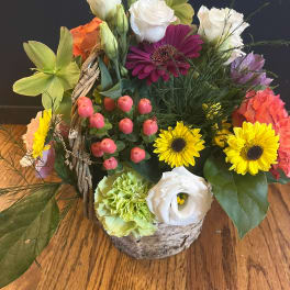 Colorful mixed flower arrangement in a birch basket with bright blooms