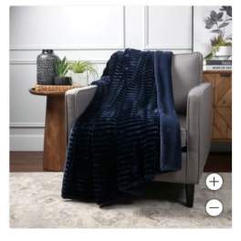Navy throw blanket draped over a gray armchair with small potted plants nearby