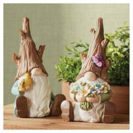 Two gnome figurines holding flowers and a butterfly decoration