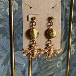 Gold bee drop earrings on a cardboard display card
