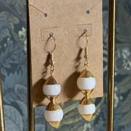 Pair of gold and white drop earrings on a display card