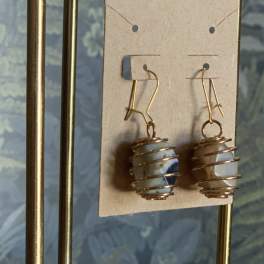 Pair of dangling earrings with wrapped stone beads on a display card