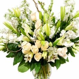 White lilies and cream roses arranged in a glass vase